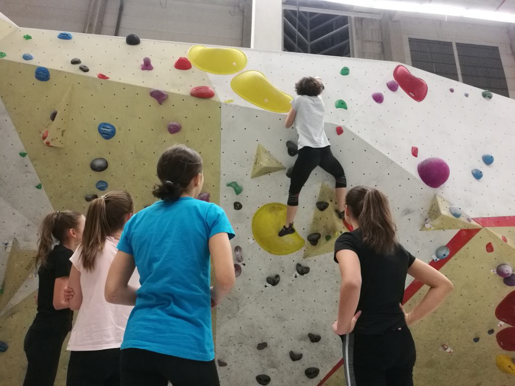 Vier Musikerinnen schauen zu, wie sich ihre Mitmusikerin Antonia an einem anspruchsvollen Boulder versucht.